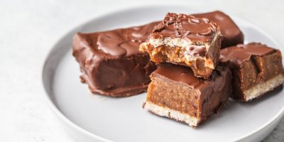 4 domácí Snickers tyčinky, servírované na hnědém talíři