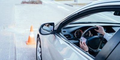 Auto, kde jde vidět ruka držící řidičský průkaz