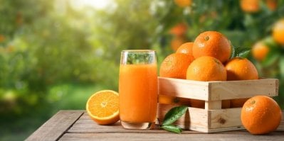 Pomeranče v bedýnce a vedle pomerančový džus