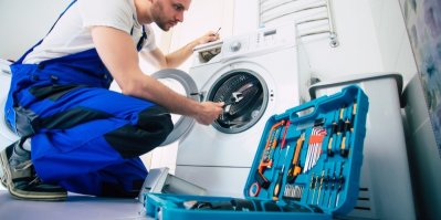 Muž v montérkách opravuje pračku