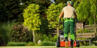 Profesionální zahradník odstraňuje z trávníku mech s pomocí vertikutátoru