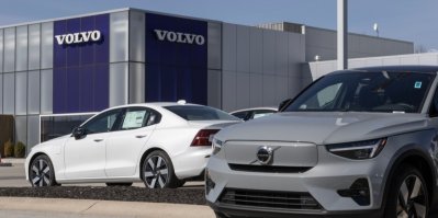 Šedé a bílé auto před prodejnou Volvo