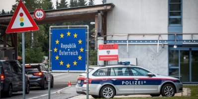 Policejní vůz, silnice a značka ukazující vjezd do Rakouska