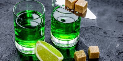 Dva koktejly výrazně zelené barvy, servírované s citronem a třtinovým cukrem