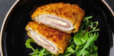 Cordon bleu, rozkrojené napůl, servírované na talíři se zeleninou