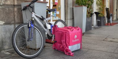 Kolo, vedle kterého stojí donáškový batoh Foodora