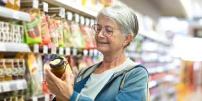 Starší žena si prohlíží džem v obchodě