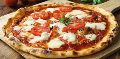 Pizza Margherita s rajčaty a mozzarellou, servírovaná na dřevěném prkénku