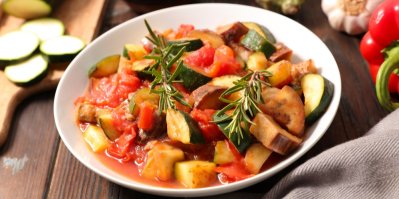 Ratatouille, servírovaný v bílém talíři, ozdobený snítkou rozmarýnu