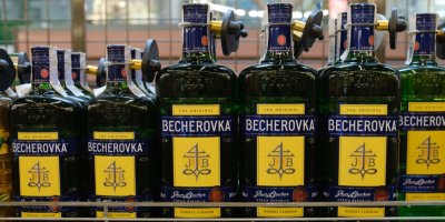 Lahev Becherovky s nalitou sklenkou před krbem