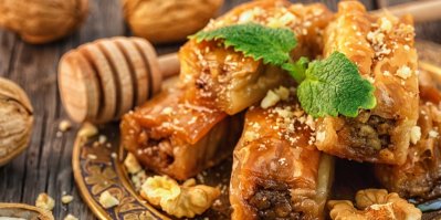 Několik kousků baklavy, servírované na talíři, ozdobené mátou