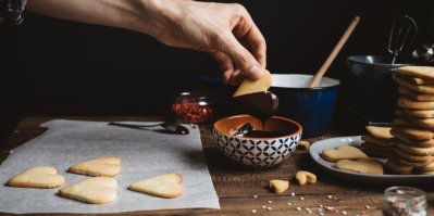 4 srdíčkové sušenky na pečicím papíru, jedna sušenka se namáčí v čokoládě