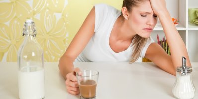 Žena pije kávu s mlékem a necítí se dobře