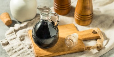 Tmavý balzamikový olej ve skleněné lahvičce na prkénku