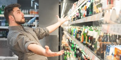 Muž před regálem s alkoholem v supermarketu