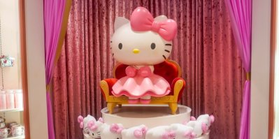Postavička Hello Kitty sedí na červeném křesle na podstavci