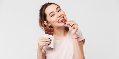 Mladá žena jí čokoládu s úsměvem