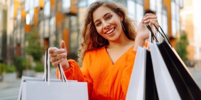 Žena se usmívá a drží v ruce spoustu nákupních tašek