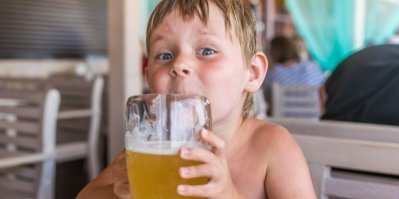 Malý kluk drží sklenici piva