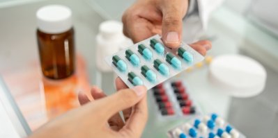 Lékárník předává ženě modro-zelené pilulky