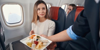 Žena v letadle dostává talíř s kousky sýra.