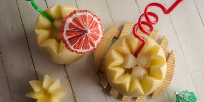 Nádoby ze žlutého melounu naplněné ledem s barevnými brčky a ozdobnými paraplíčky