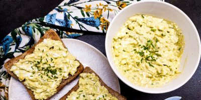 2 toasty, namazané cottage pomazánkou, servírované na bílém talíři, v pozadí miska s pomazánkou