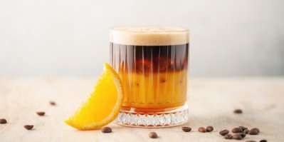 Sklenice s espresso orange, kolem sklenice zrnka kávy