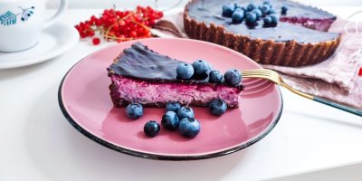 Borůvkový cheesecake, ozdobený borůvkami, servírovaný na růžovém talíři