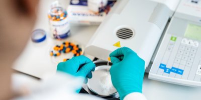 Pracovník v gumových rukavicích pracuje v laboratoři.