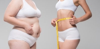 Štíhlá žena se dívá do zrcadla na své ploché břicho