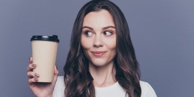 Ruka pokládá hrnek s kávou na podtácek