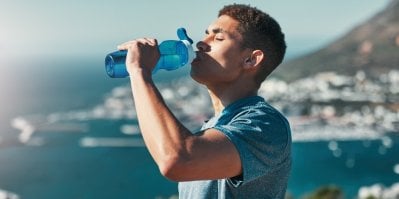 Muž pije zbarvený nápoj s elektrolyty ze sklenky