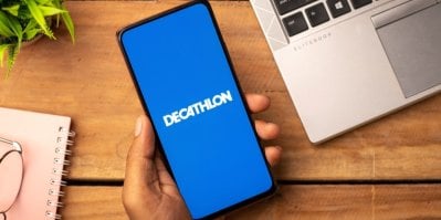 Ruka drží chytrý telefon s otevřenou aplikací Decathlon