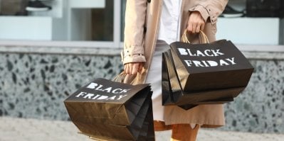 Žena drží v rukou velké nákupní tašky s nápisem Black Friday