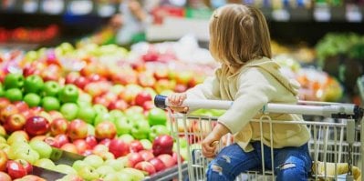 Holčička sedí v nákupním vozíku v supermarketu