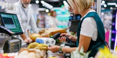 Pokladní v supermarketu skenuje čárový kód potravin