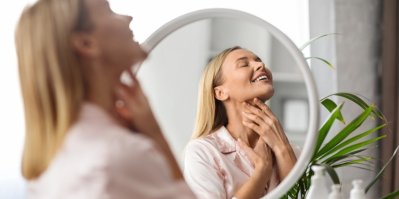Žena ve středních letech masíruje bradu pomocí rukou