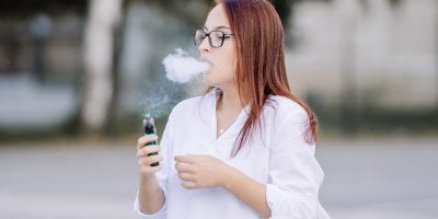 Mladá žena kouří elektronickou cigaretu