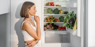 Žena zamyšleně stojí před ledničkou