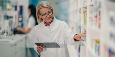Lékárnice v lékárně kontroluje regál s medikamenty