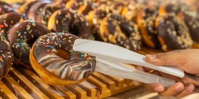 Člověk vytahuje donut z regálu pomocí kleští