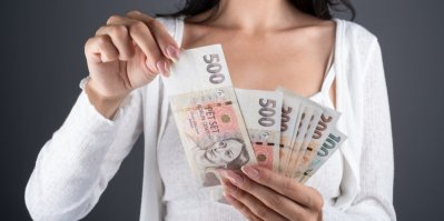Mladá žena drží v rukou české bankovky