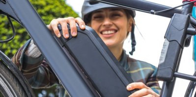 Mladá žena drží baterii elektrokola připevněnou na rámu