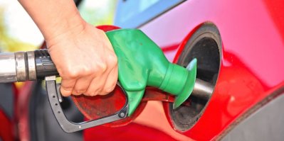 Muž tankuje palivo do červeného vozu na benzinové stanici