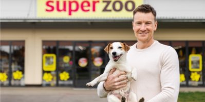 Muž drží v náručí psa před budovou Super zoo