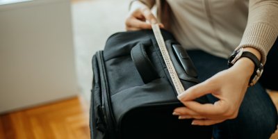 Žena měří krejčovským metrem šířku kufru
