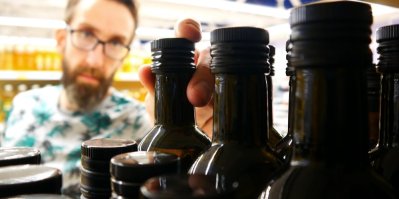 Muž vybírá v supermarketu olivový olej