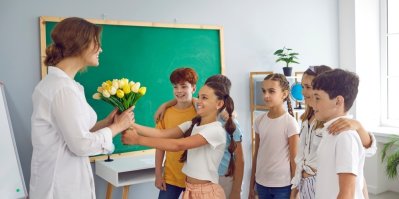 Žáci ve třídě dávají učitelce květiny