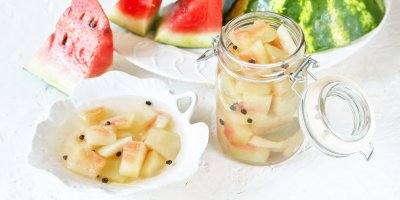 Nakládané melounové slupky v misce a sklenici, okolo meloun